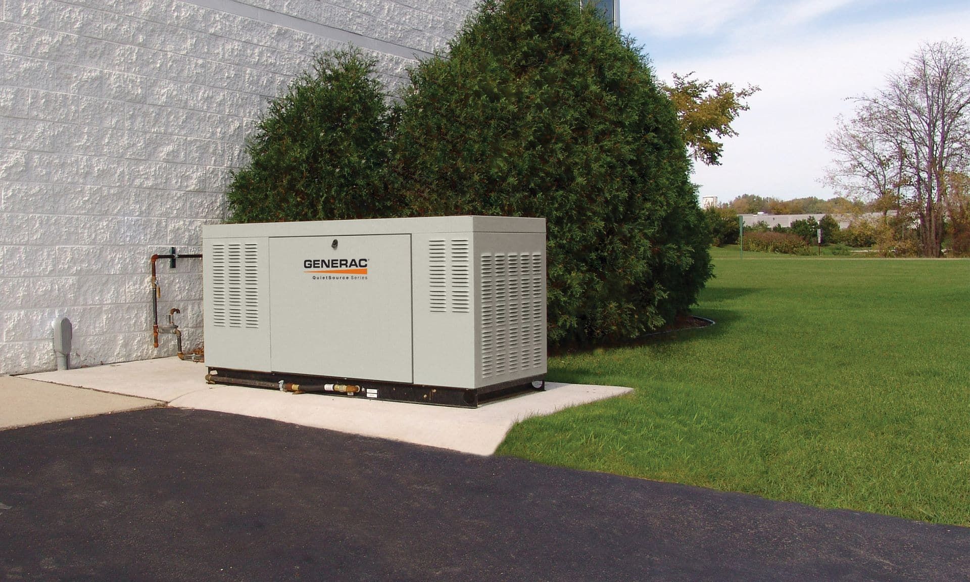A Generac standby generator installed on a pad beside a house